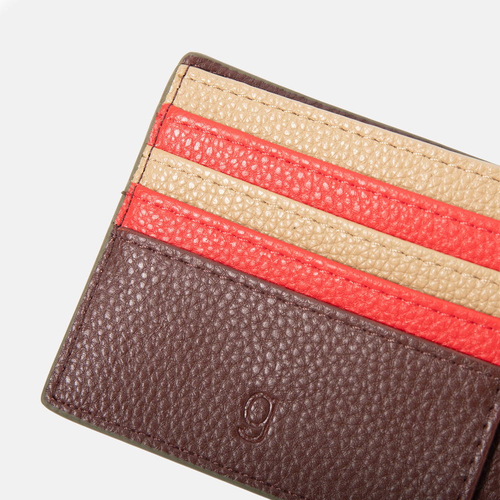 Close-up of a dark purple leather wallet with a red and sand card slots on a white background