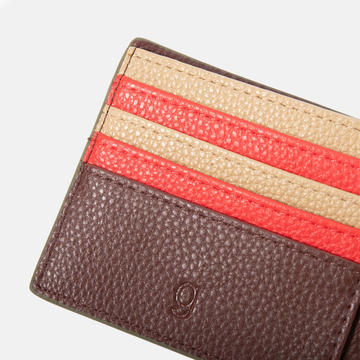 Close-up of a dark purple leather wallet with a red and sand card slots on a white background