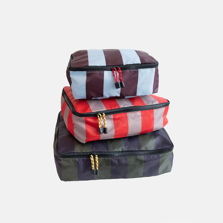 Three striped packing cubes stacked on a white background
