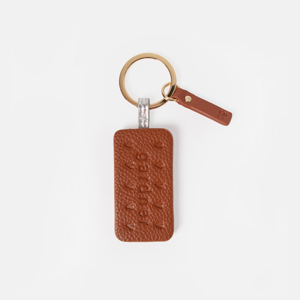 A brown bourbon biscuit style leather- look keyring with embossed hearts & gardner lettering, attached to a gold-tone split keyring and a small matching leather tag, shown on a clean white background.