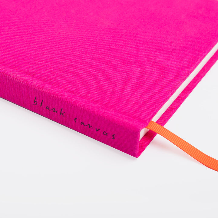 Pink notebook with 'blank canvas' text and an orange ribbon on a white background