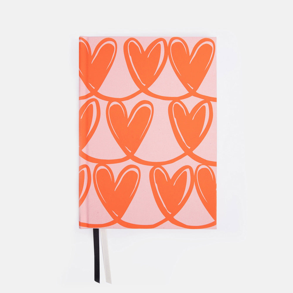 Notebook with orange heart pattern on pink cover against a white background