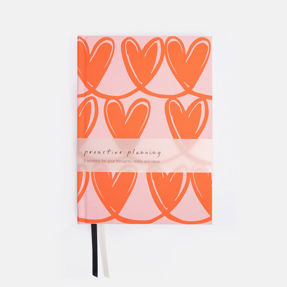 Notebook with orange heart pattern on a pink background
