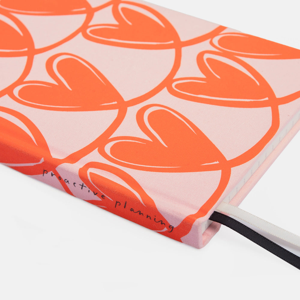 Notebook with orange heart pattern on a pink background