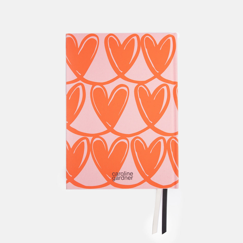 Notebook with orange heart pattern on a pink cover, brand 'caroline gardner' visible