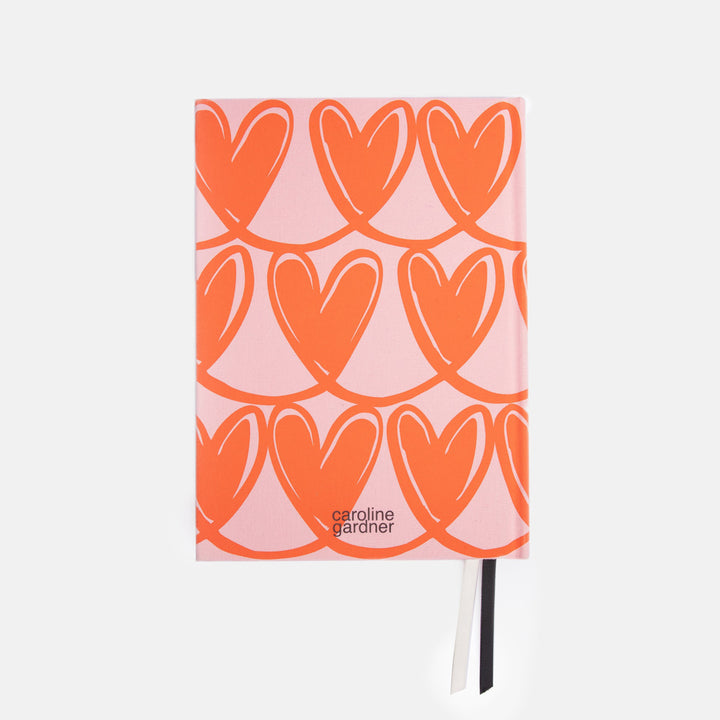Notebook with orange heart pattern on a pink cover, brand 'caroline gardner' visible