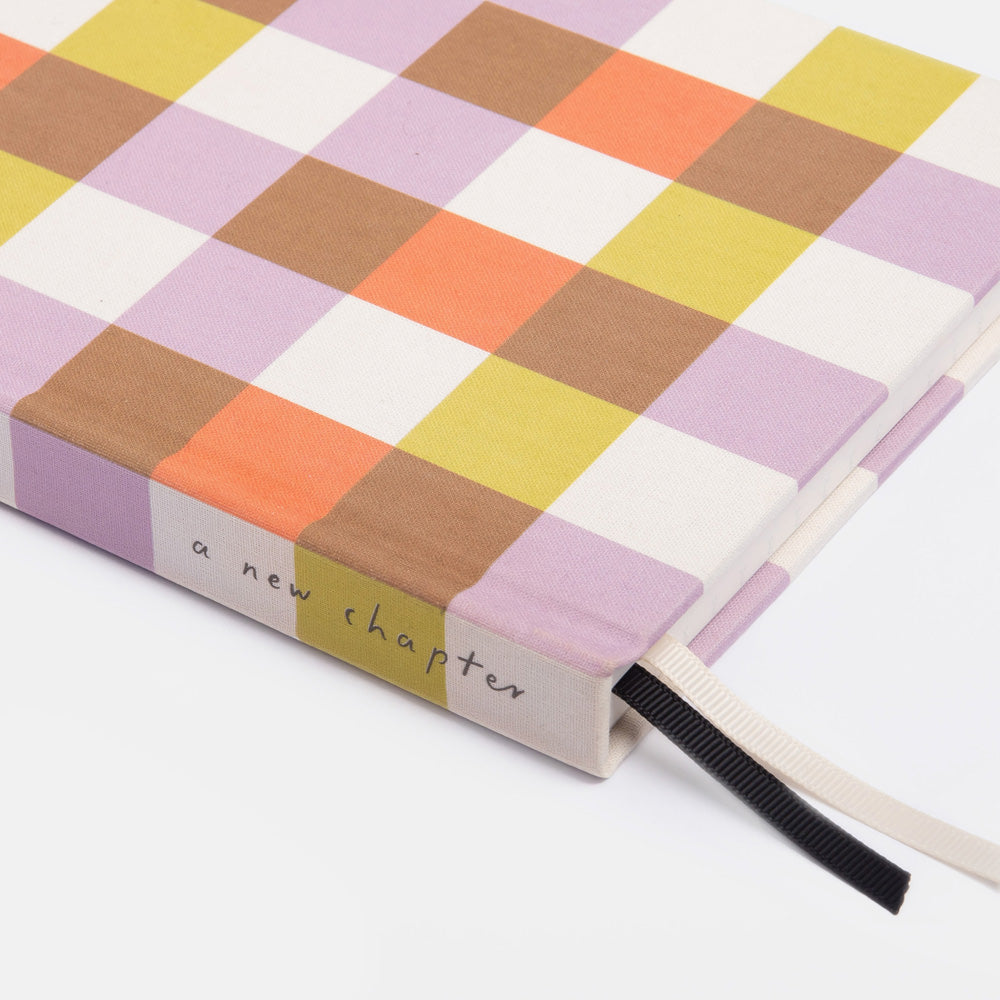 Checkered notebook with 'a new chapter' text on a white background