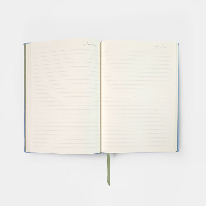 An open lined notebook with blank cream-colored pages, a blue cover edge, and a green ribbon bookmark, photographed on a clean white background.