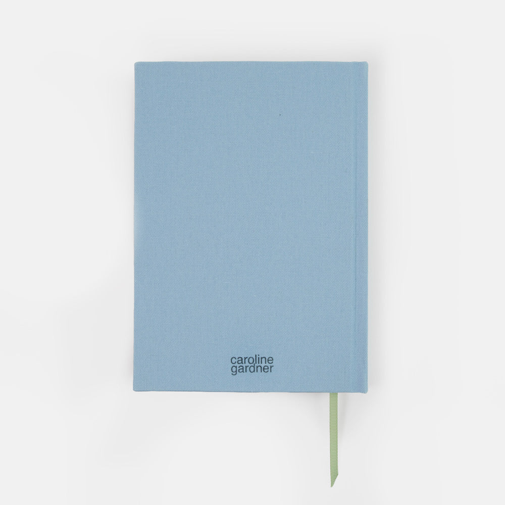A light blue hardcover notebook by Caroline Gardner with a green ribbon bookmark, shown against a plain white background.