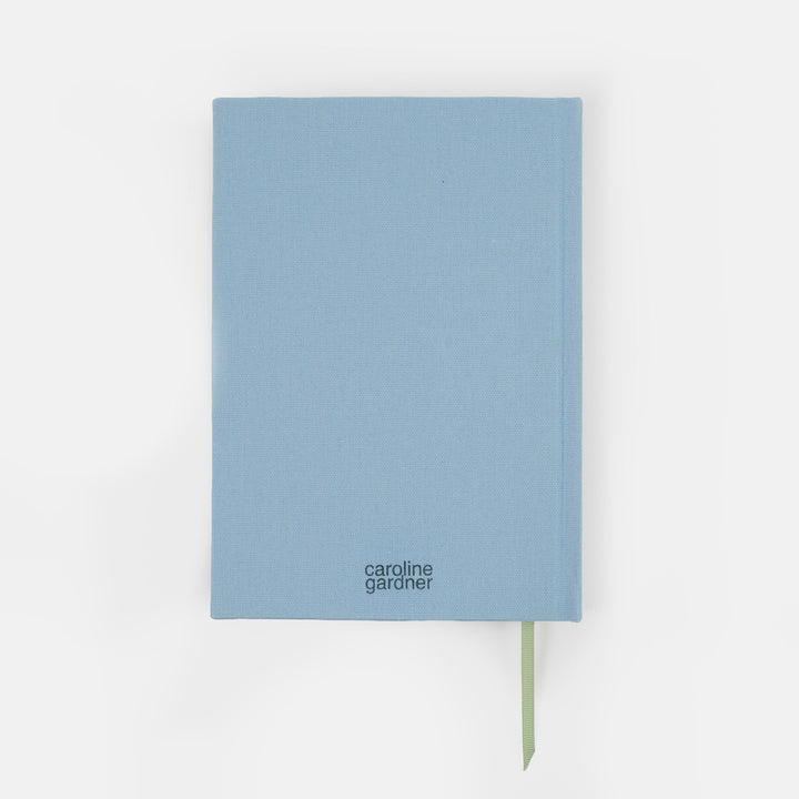 A light blue hardcover notebook by Caroline Gardner with a green ribbon bookmark, shown against a plain white background.
