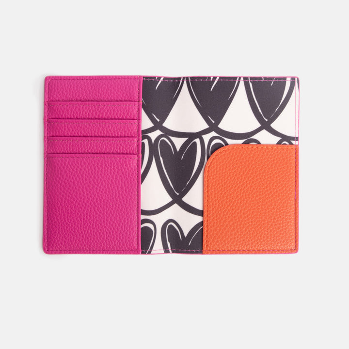 internal of passport holder with bright pink cover, monochrome hearts print lining and orange corner pocket