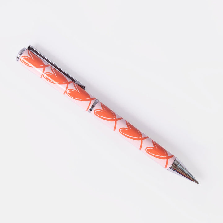 ballpoint pen with orange looped hearts on a pink background
