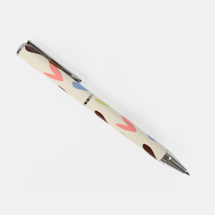 A cream-colored ballpoint pen with a retro pattern of colorful abstract shapes, featuring a silver metal clip and tip, shown on a light gray background.