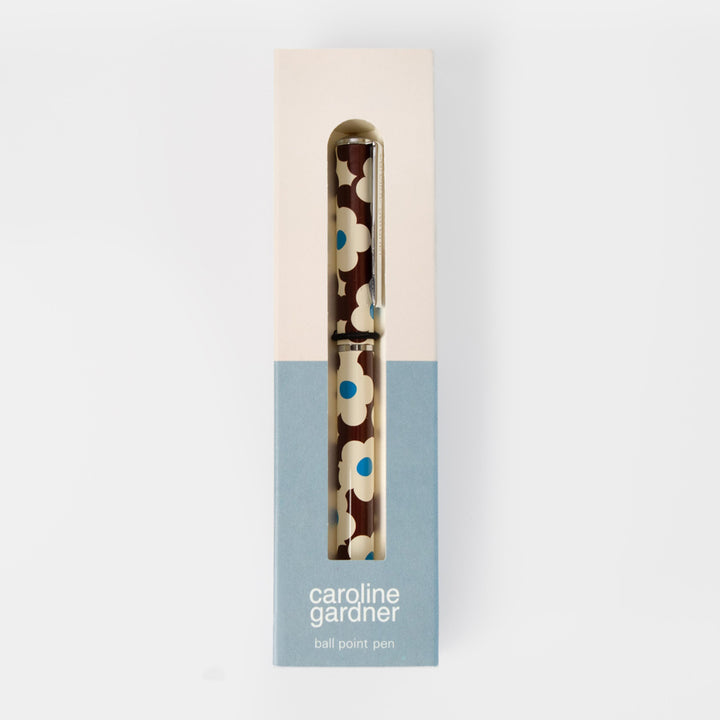A Caroline Gardner ball point pen with a brown, cream, and blue floral pattern, presented in its original packaging box against a light gray background.