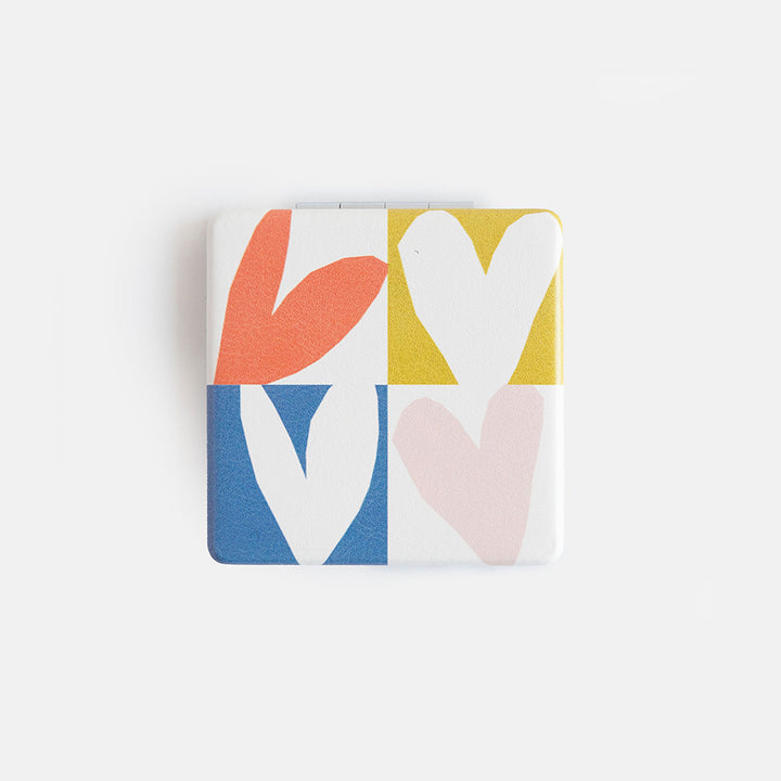 printed leather look PU square compact pocket mirror in a multi coloured hearts print, with 2 mirrors and magnetic fastening