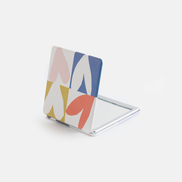 printed leather look PU square compact pocket mirror in a multi coloured hearts print, with 2 mirrors and magnetic fastening