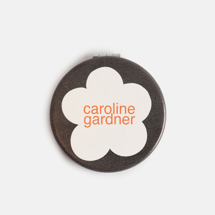 printed leather look PU round compact pocket mirror in a cream flower over charcoal print, with 2 mirrors and magnetic fastening