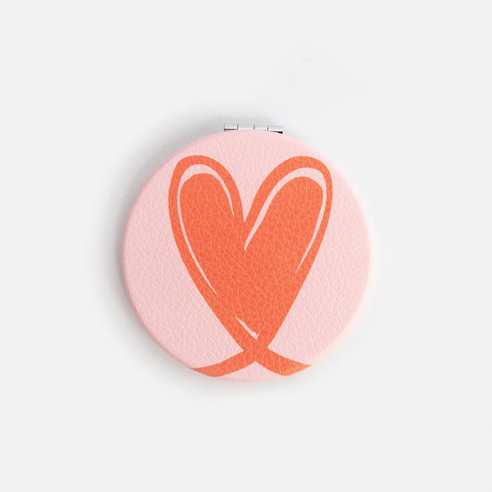 Compact mirror with a red heart design on a white background