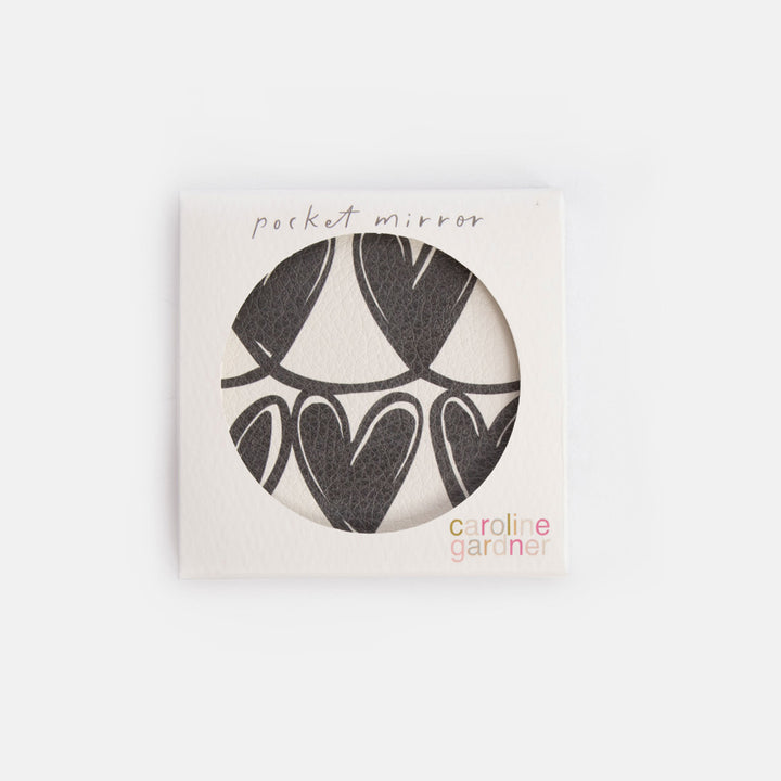 Pocket mirror with black heart design in a white box, branded 'caroline gardner'.