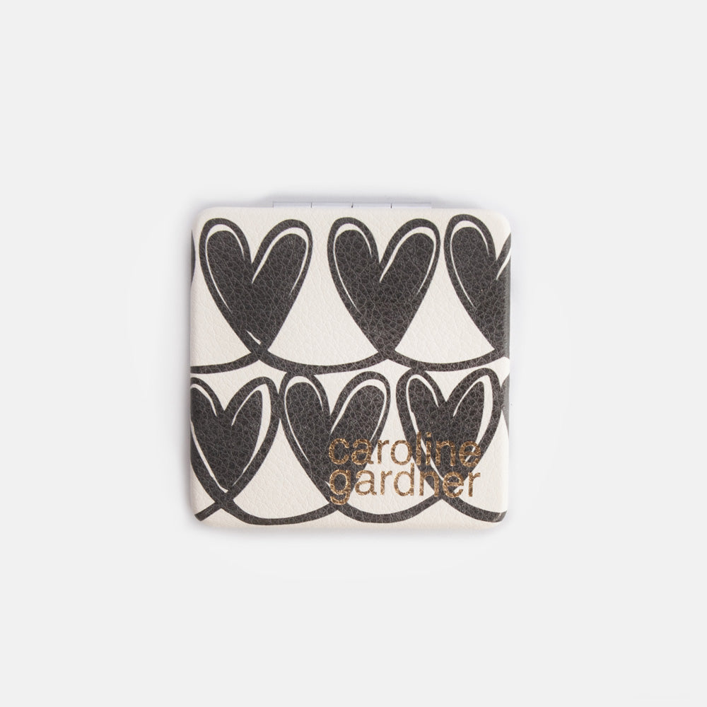 Square compact mirror with heart pattern and 'caroline gardner' branding on a white background