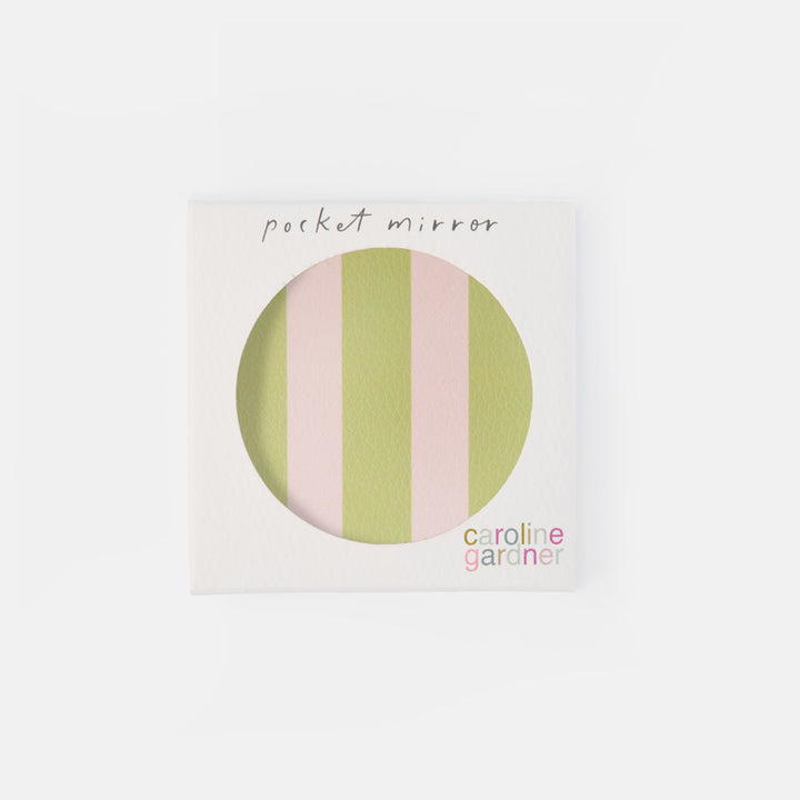 A square white product box with a circular cutout showing pastel vertical stripes in light green and pink. Handwritten text at the top reads 'pocket mirror,' and the brand name 'caroline gardiner' appears at the bottom right.