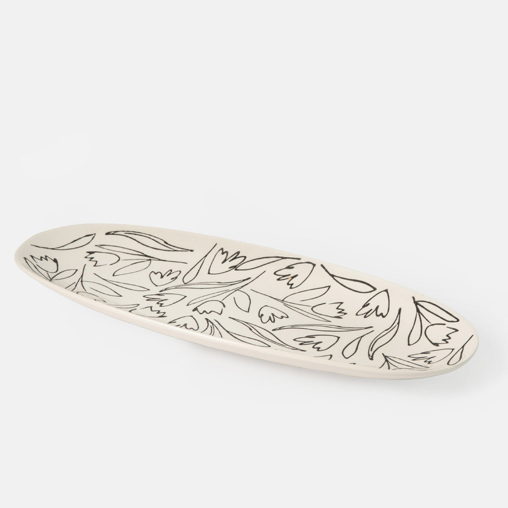 oval shaped serving platter with black flower and leaf design on a cream base