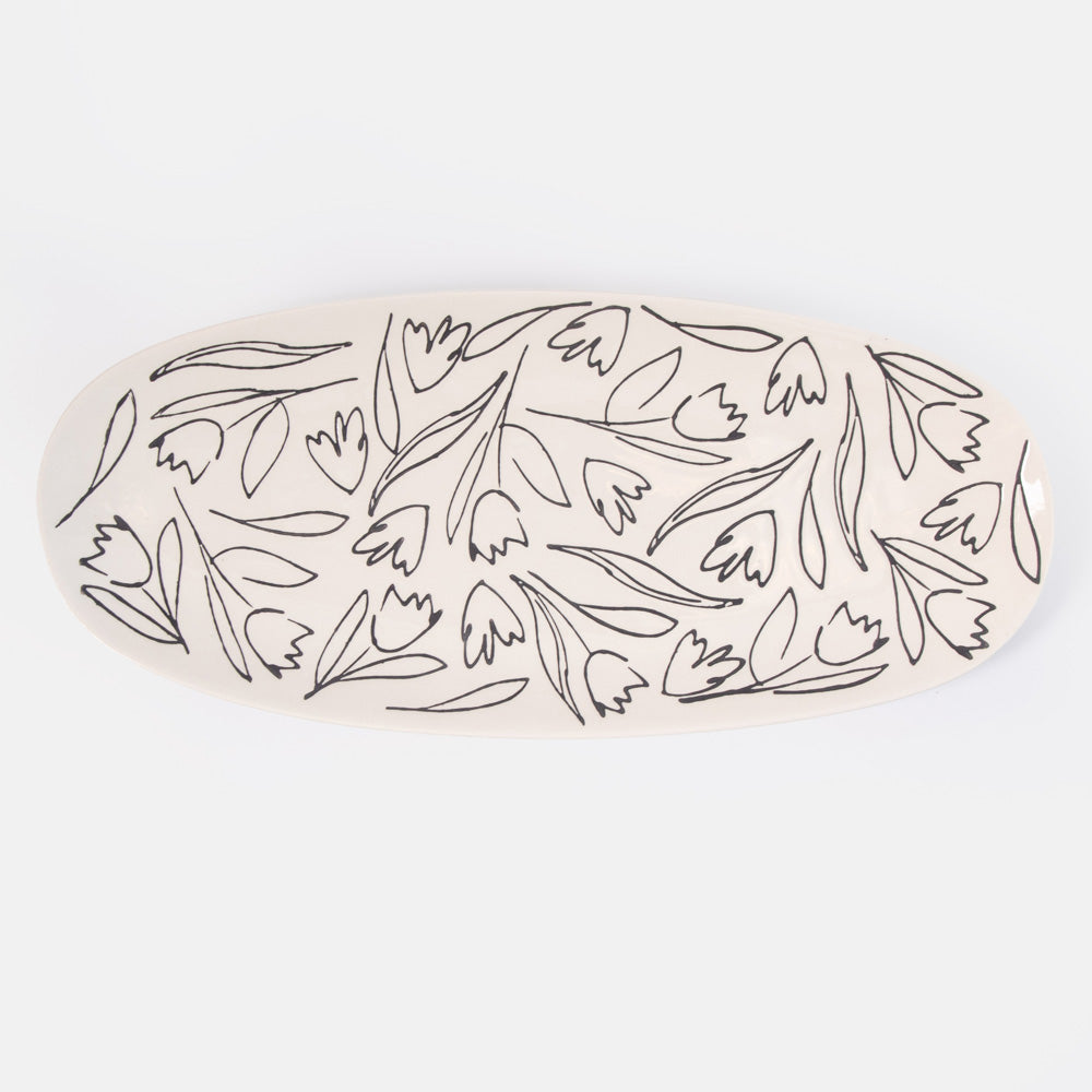 oval shaped serving platter with black flower and leaf design on a cream base