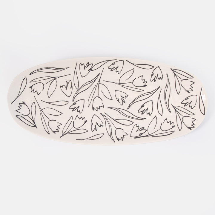 oval shaped serving platter with black flower and leaf design on a cream base