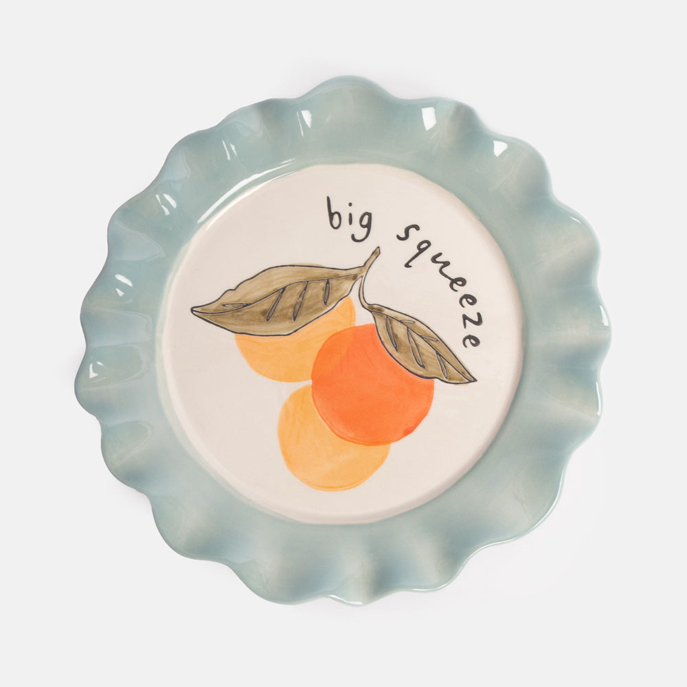 Ceramic plate with an illustration of 3 oranges with leave and 'big squeeze' text, finished with a light blue scalloped edge rim