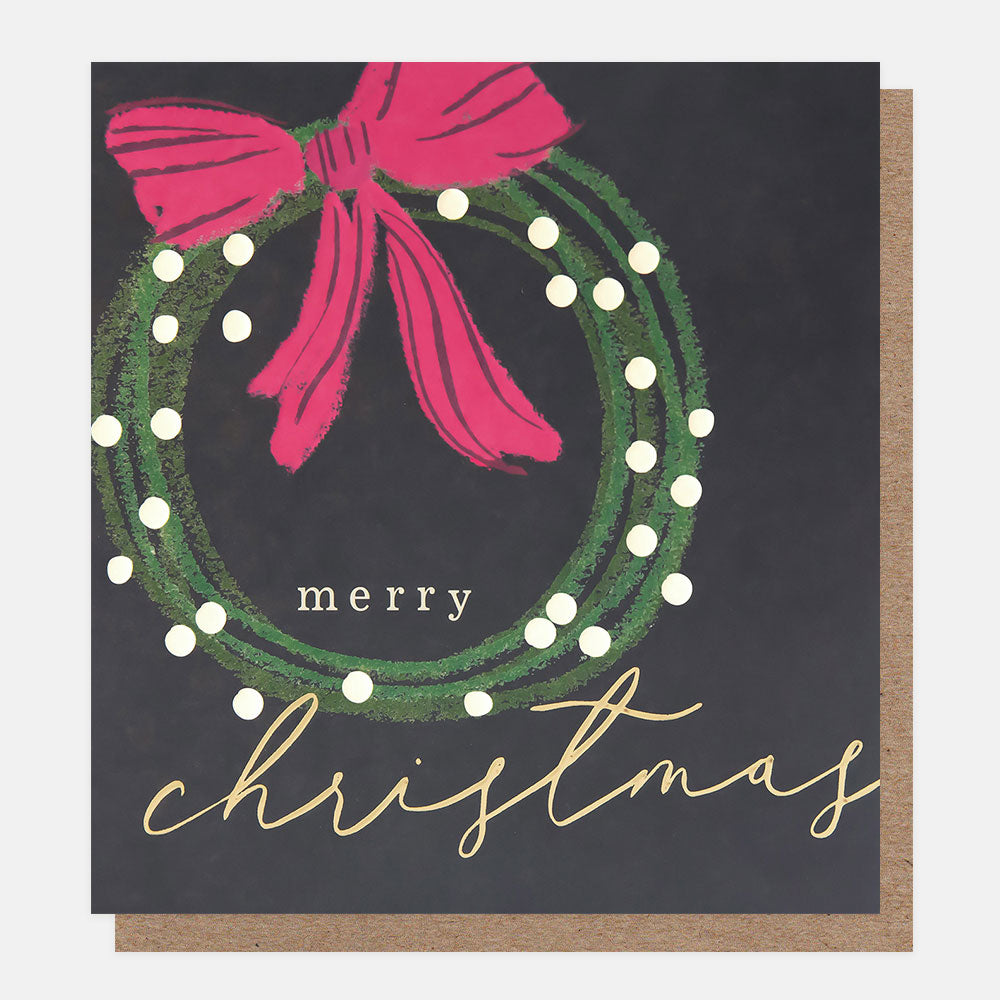 Christmas card featuring a green wreath with white spots and a pink bow on a dark blue background