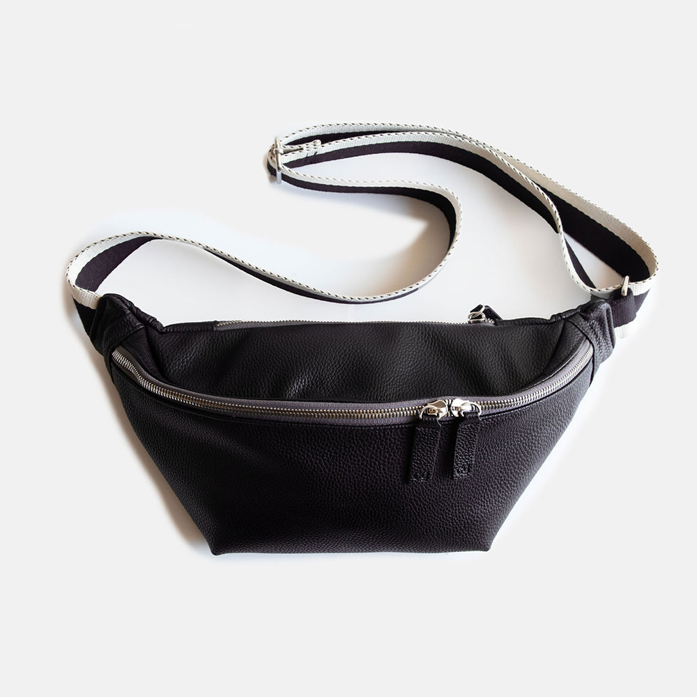 black vegan leather crossbody bag with white and black striped fabric strap and front zip closure