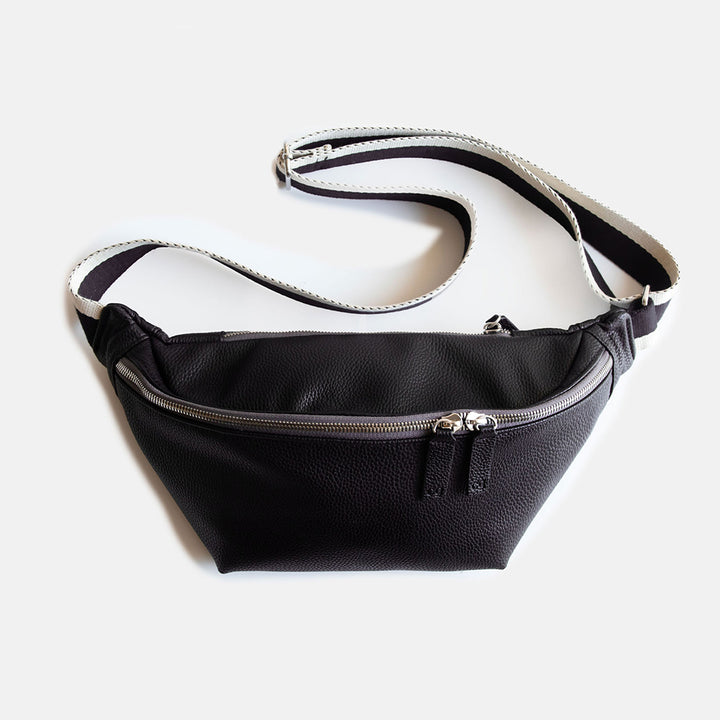 black vegan leather crossbody bag with white and black striped fabric strap and front zip closure