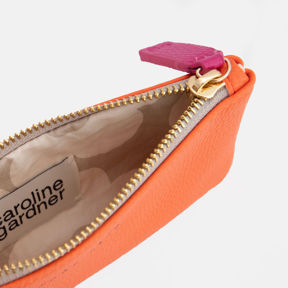 close up of orange pencil case with flower print lining and 'caroline gardner' branding