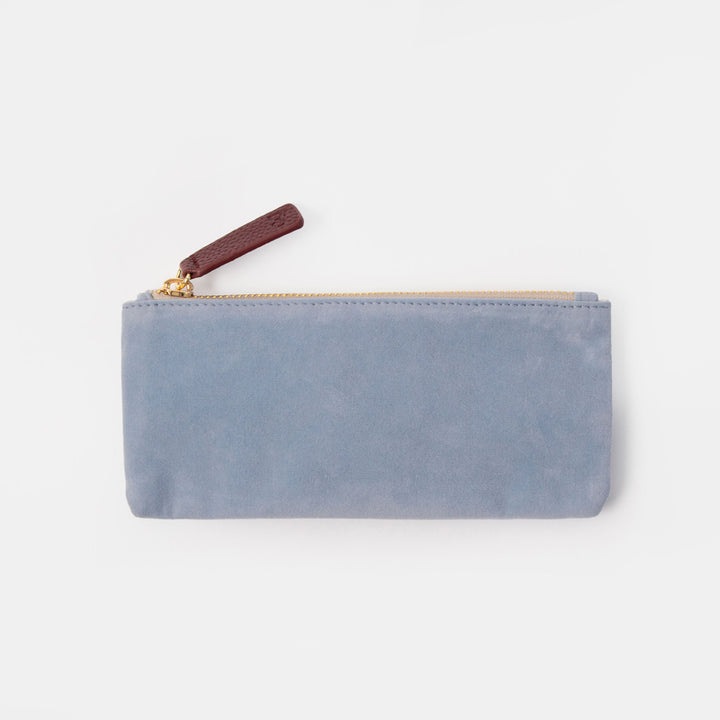 A light blue suede zip pouch with a gold zipper and a dark brown leather pull tab, shown on a plain light gray background.