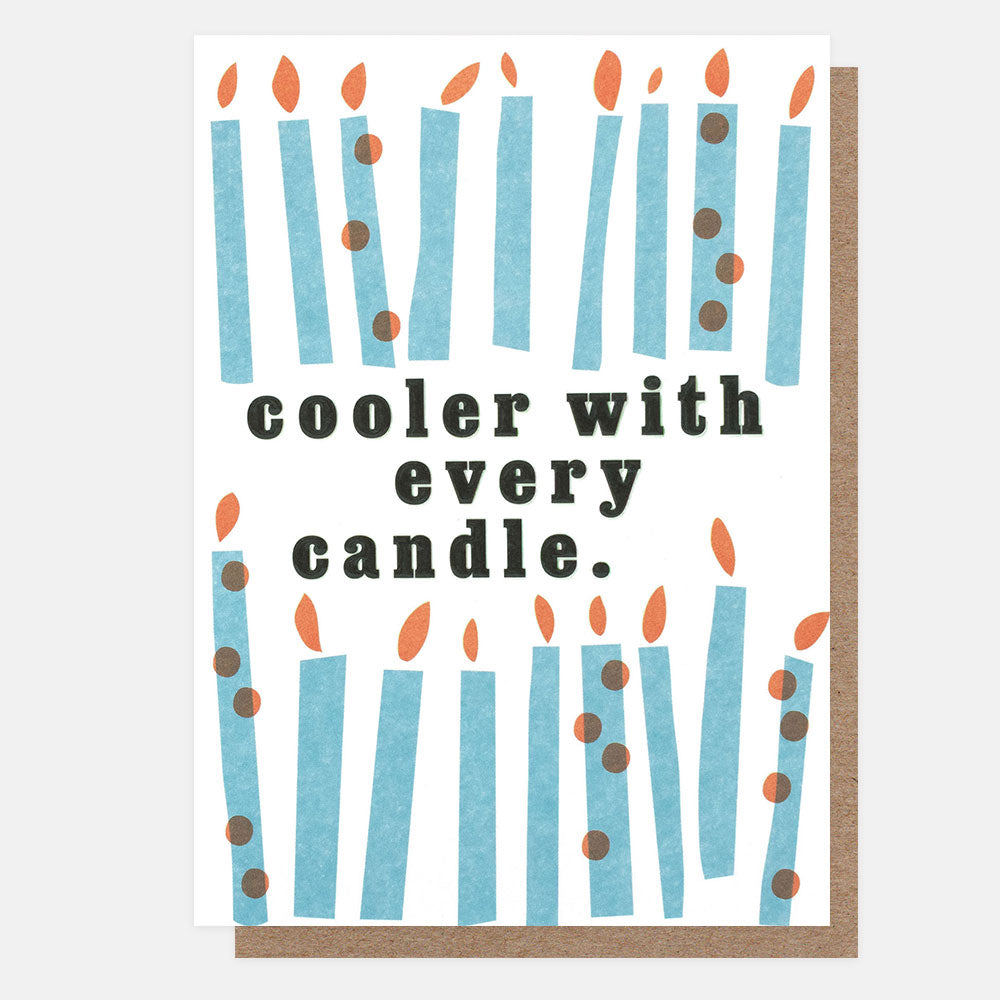 A greeting card with a kraft envelope, featuring an illustration of blue candles with orange flames and the text 'cooler with every candle.' in dark gray lettering.