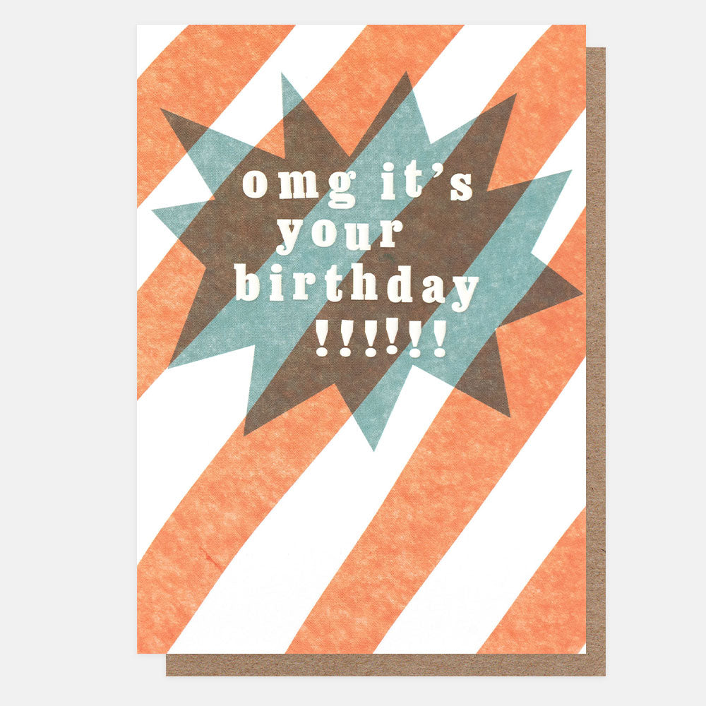 A greetings card with bold orange diagonal stripes and overlapping teal and brown starbursts, with the text 'omg it's your birthday!!!!!!' in white embossed lettering, shown with a brown kraft envelope behind it.