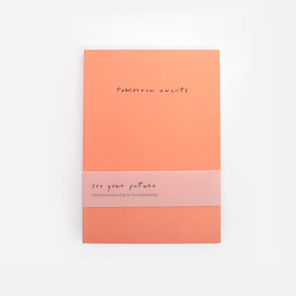 orange notebook with 'tomorrow awaits' text on a white background