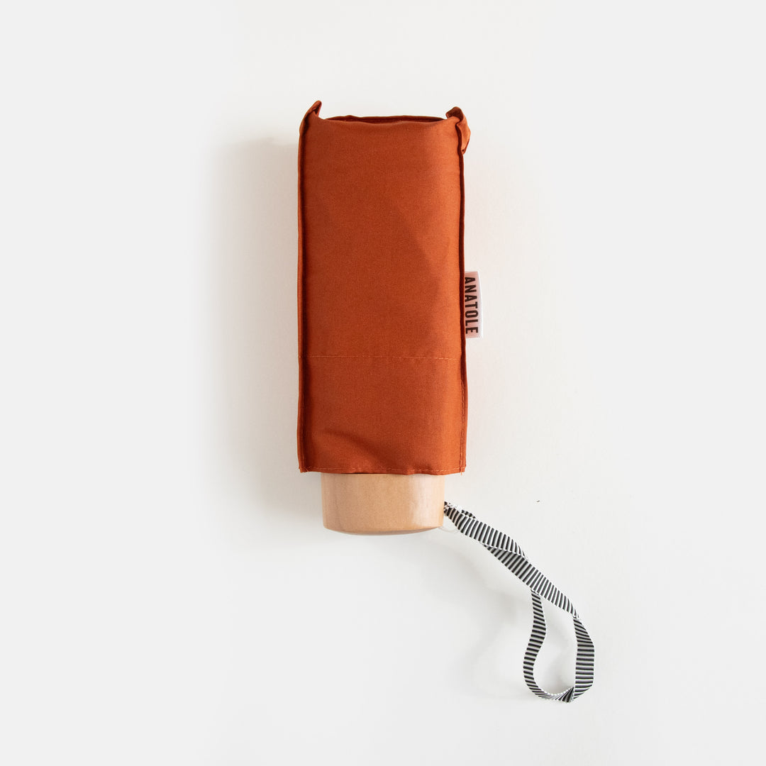 rust orange compact folding umbrella packed in its sleeve