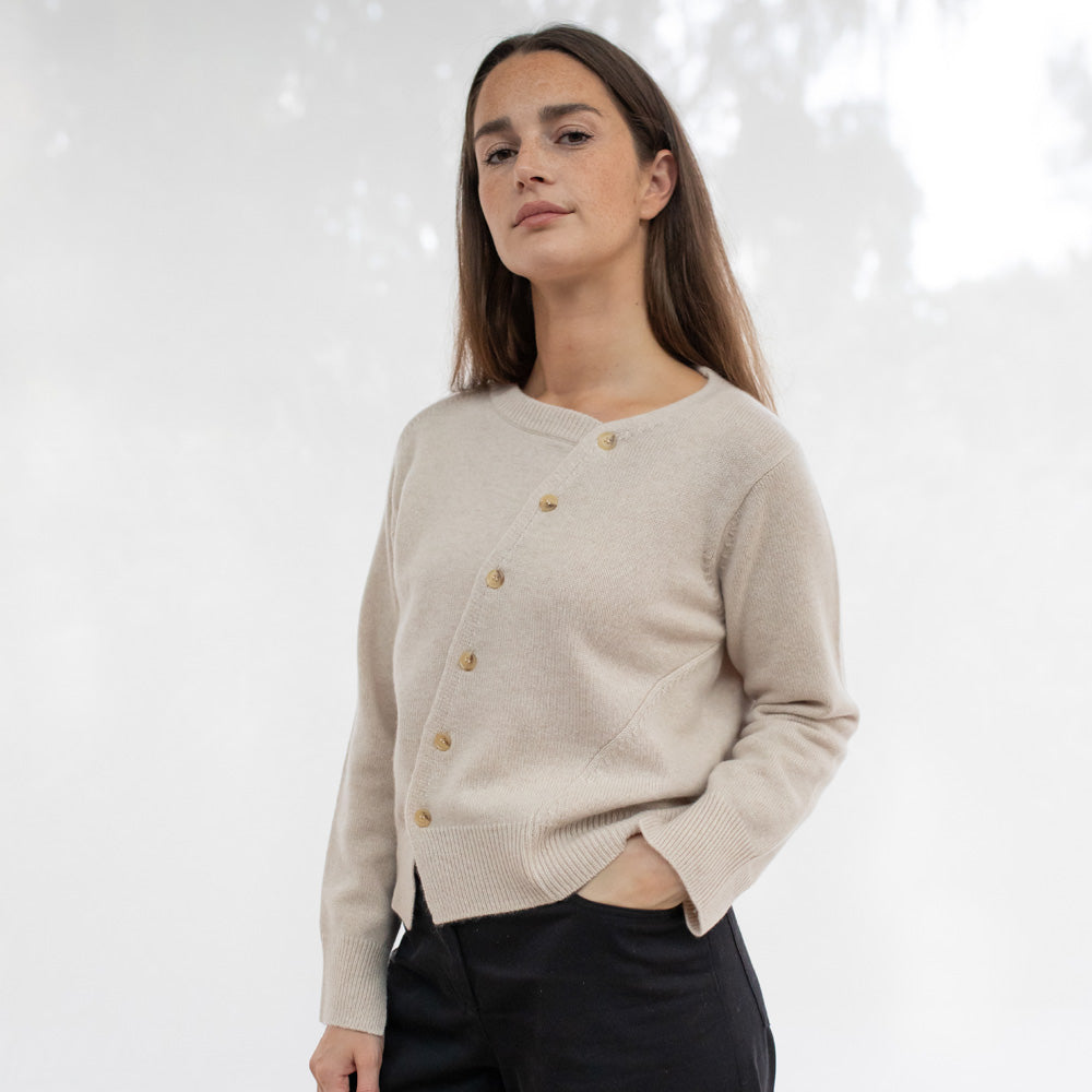 Woman wearing a beige asymmetrical cardigan with buttons 