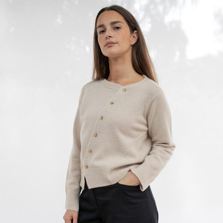 Woman wearing a beige asymmetrical cardigan with buttons 