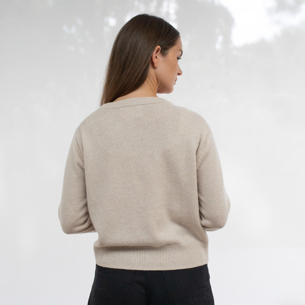 Woman wearing a beige sweater against a white background