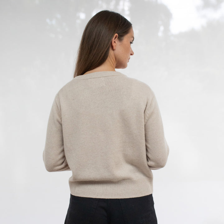 Woman wearing a beige sweater against a white background