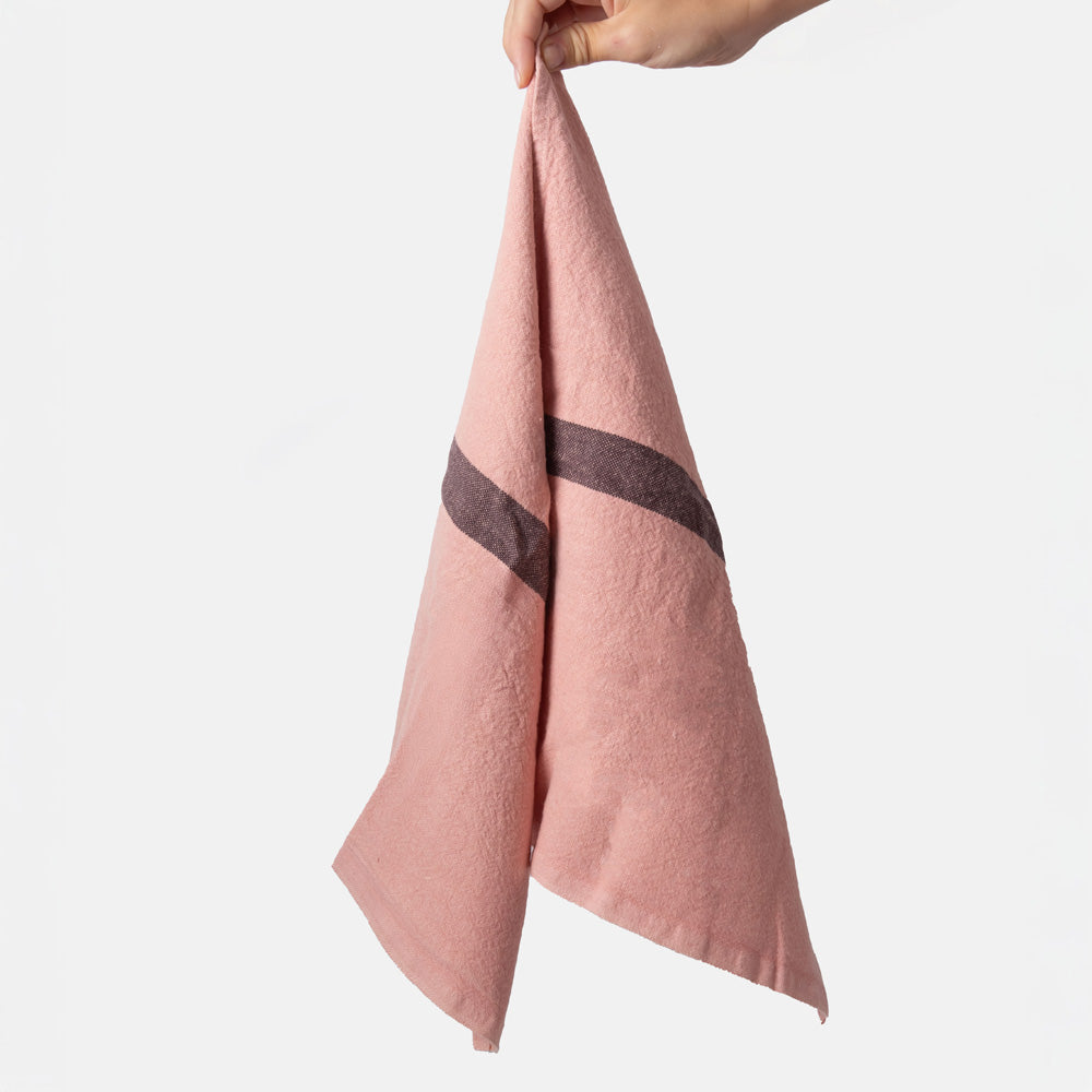 Pink placemat with a dark grey stripe held by a hand on a white background