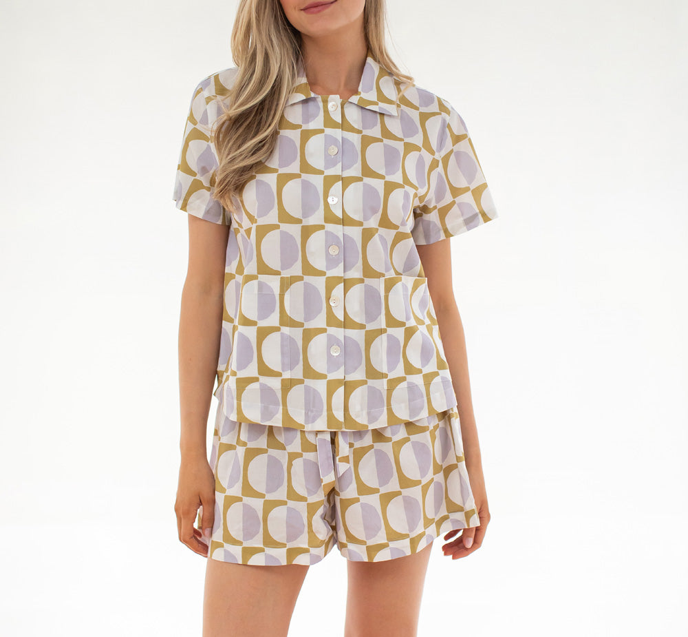 Woman wearing a patterned shirt and shorts set on a white background