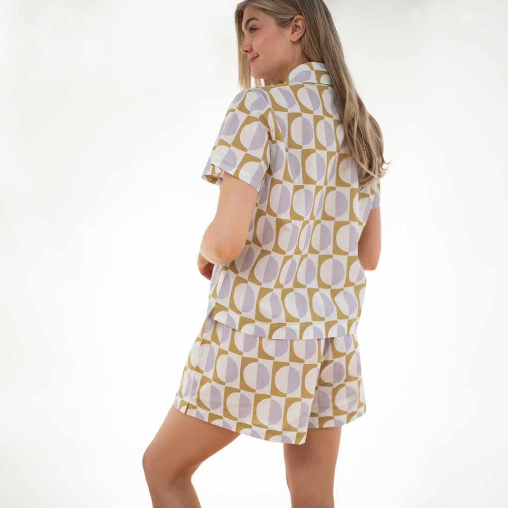 Woman wearing a patterned shirt and shorts set on a white background