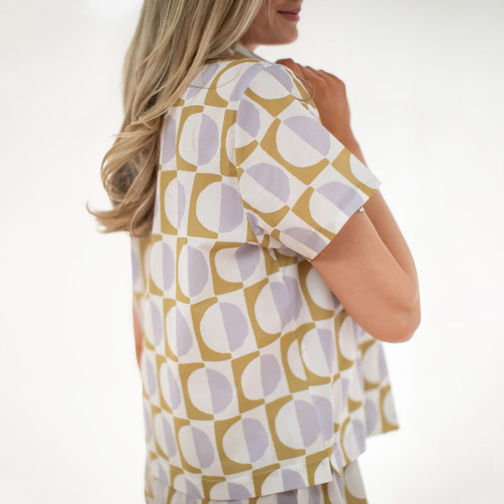 Woman wearing a patterned shirt with geometric design on a white background
