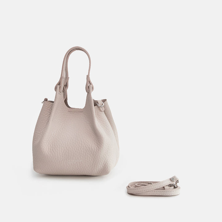 white leather tote style handbag with a spare matching strap on a white background