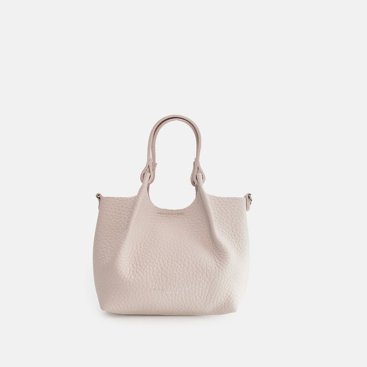 white leather tote style handbag with a spare matching strap on a white background