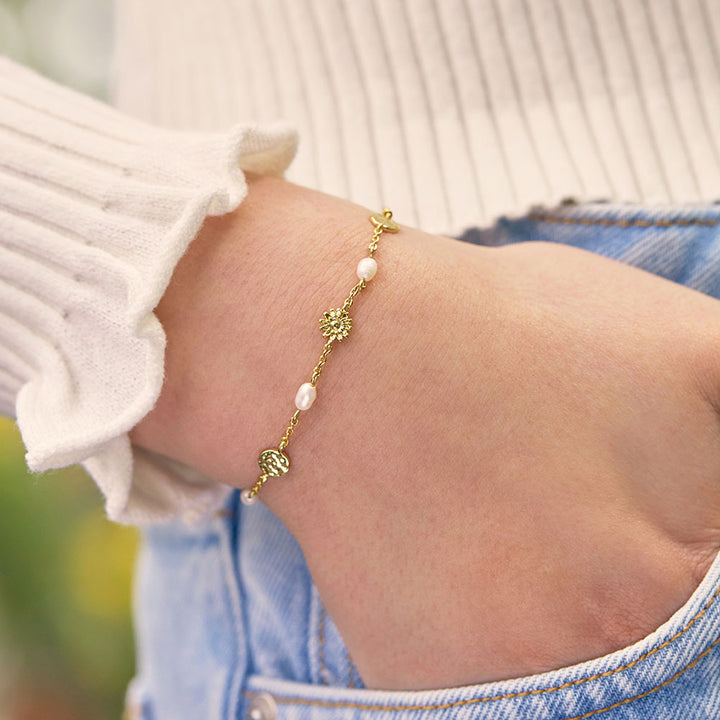 gold plated fine bracelet with 2 hammered disc charms, 1 flower charm and 4 pearls, with an adjustable slider