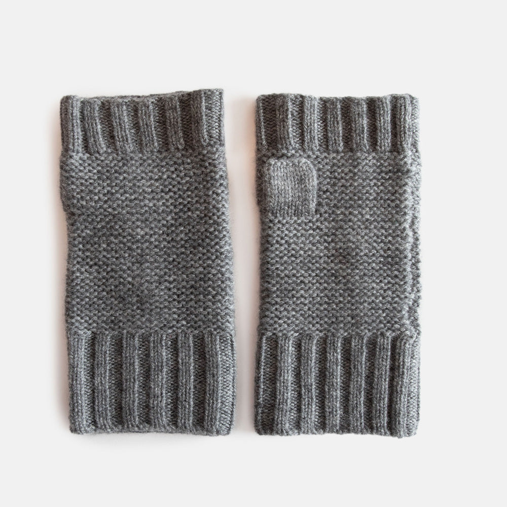 Pair of grey knitted fingerless gloves on a light beige background